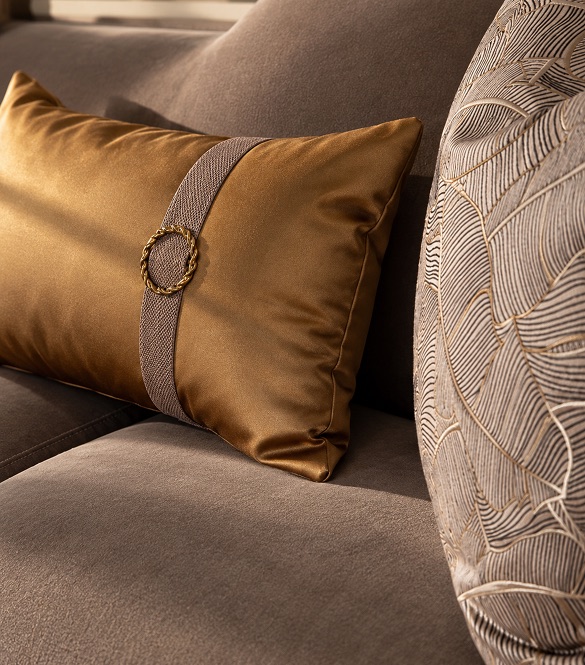 Abode Home fabrics — satin pillow with braided gold buckle and embroidered leaf pillow on a velvet sofa
